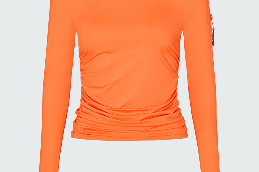 Orange long-sleeve sun protective tee with side ruching and arm zip pocket