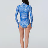 Woman wearing a long-sleeve bodysuit in a blue bandana print with white front zipper.