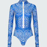A long-sleeve bodysuit in a blue bandana print with white front zipper.