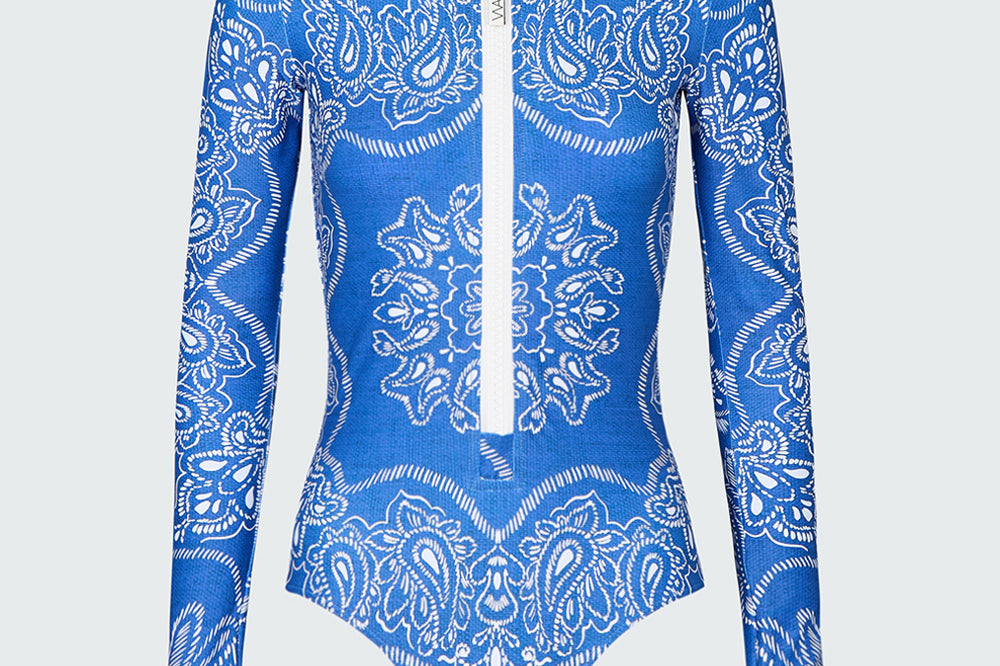 A long-sleeve bodysuit in a blue bandana print with white front zipper.