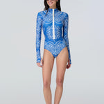 Woman wearing a long-sleeve bodysuit in a blue bandana print with white front zipper.