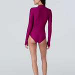 Back view of a woman wearing a long sleeve bodysuit in dark berry with a pink front zipper.