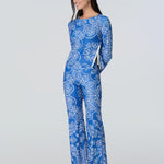 A woman in a blue and white  bandana-print long sleeve top with side zipper and pants.