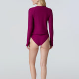 Woman wearing a long sleeve sun protective swim tee and bikini bottom in dark berry.