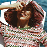 Pink & green wavy stripe sun hat, swim top with green cuffs, bikini bottom, dock by water