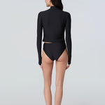 Back view of a woman wearing long sleeve mock neck zip front black rashguard with a yellow zipper and black bikini bottom.