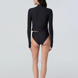 Back view of a woman wearing long sleeve mock neck zip front black rashguard with a yellow zipper and black bikini bottom.