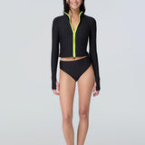Front view of a woman wearing long sleeve mock neck zip front black rashguard with a yellow zipper and black bikini bottom.