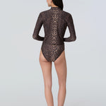 Back view of a woman wearing a long sleeve leopard print rashguard and bikini bottom.