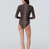 Back view of a woman wearing a long sleeve leopard print rashguard and bikini bottom.