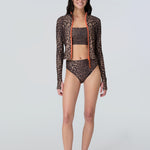 Front view of a woman wearing a long sleeve leopard print zip front rashguard, bralette, and bikini bottom.