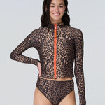 Front view of a woman wearing a long sleeve leopard print zip front rashguard and bikini bottom.
